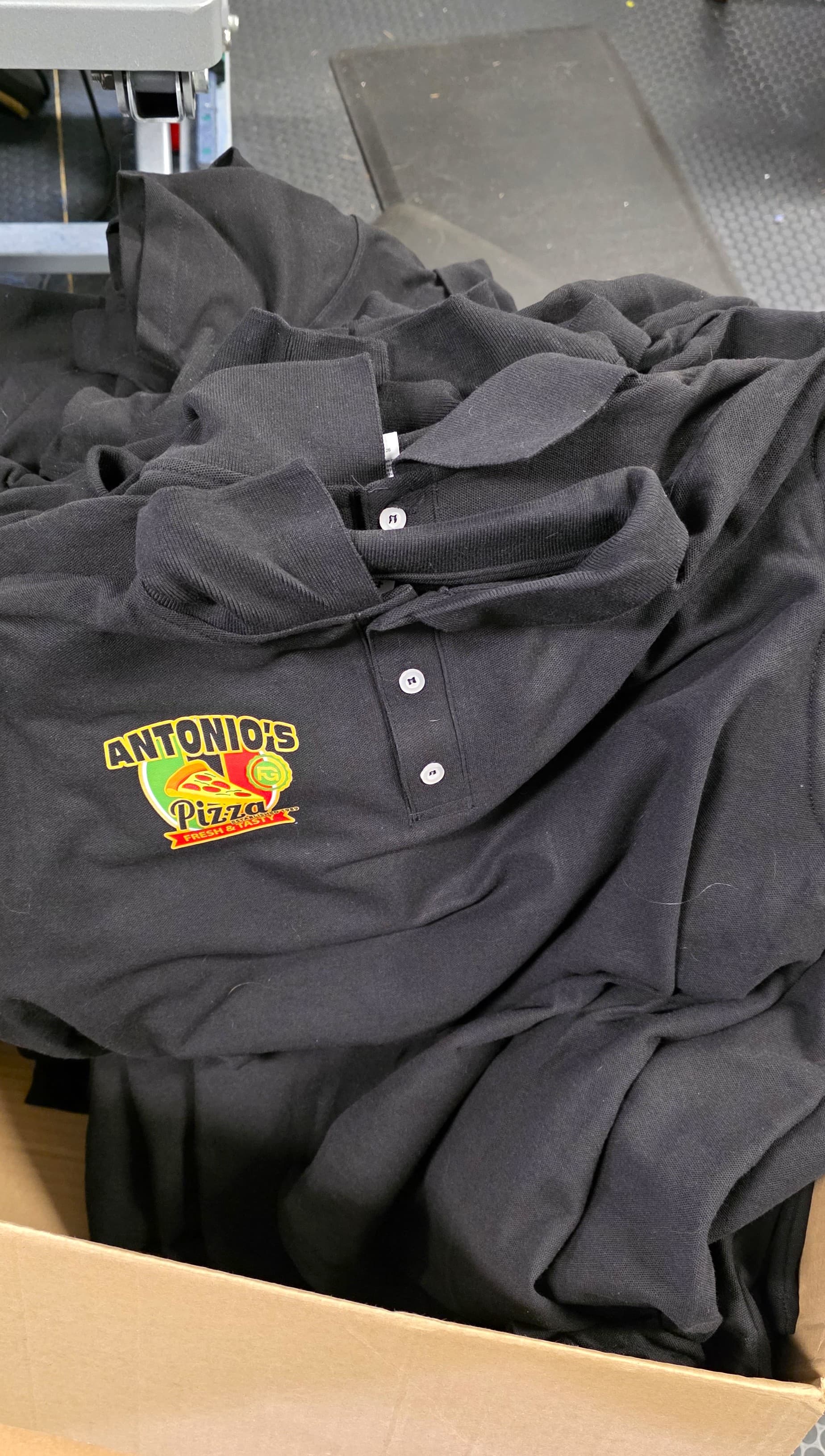 Box of finished custom-printed Antonio's Pizza staff polos by Print Habit, Morgantown PA