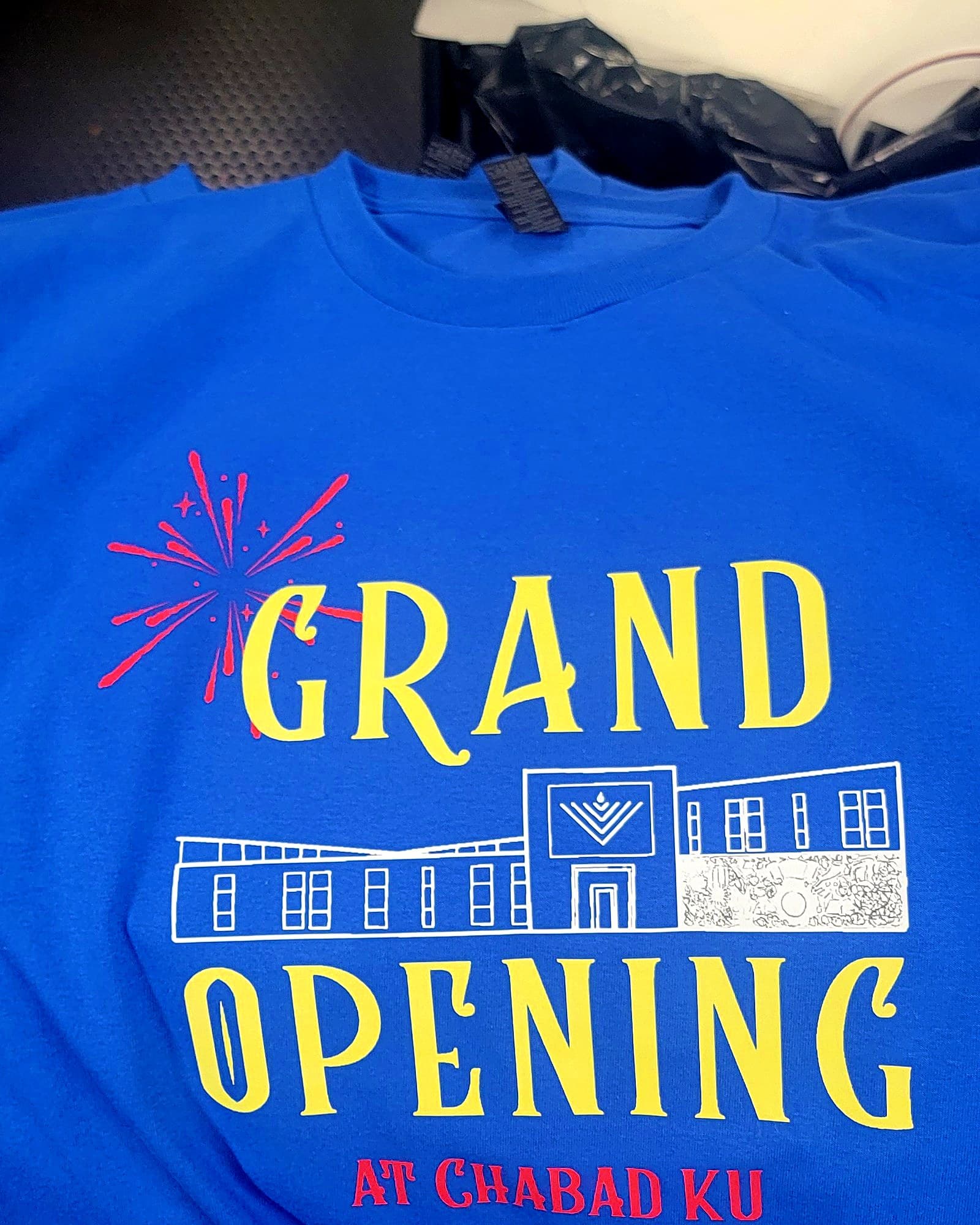 Multi-color grand opening design printed on a royal blue t-shirt