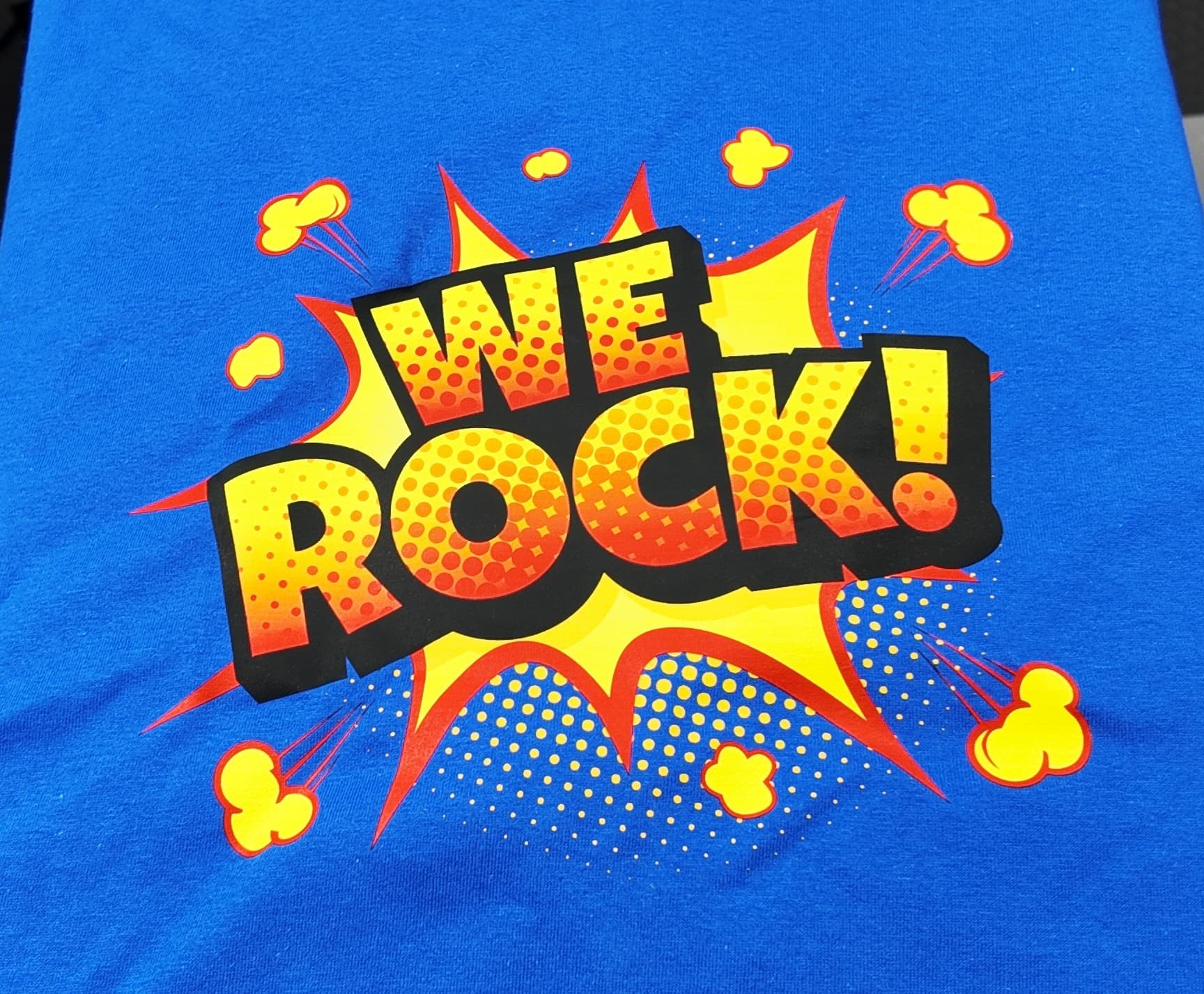 Comic-style 'WE ROCK!' full-color halftone DTF print on a royal blue t-shirt — Print Habit, Coatesville PA