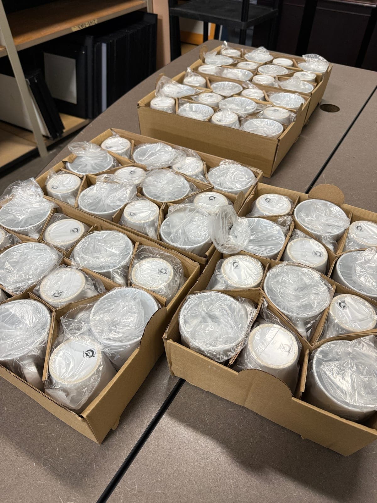 Boxes of plastic-wrapped blank sublimation mugs waiting to be decorated