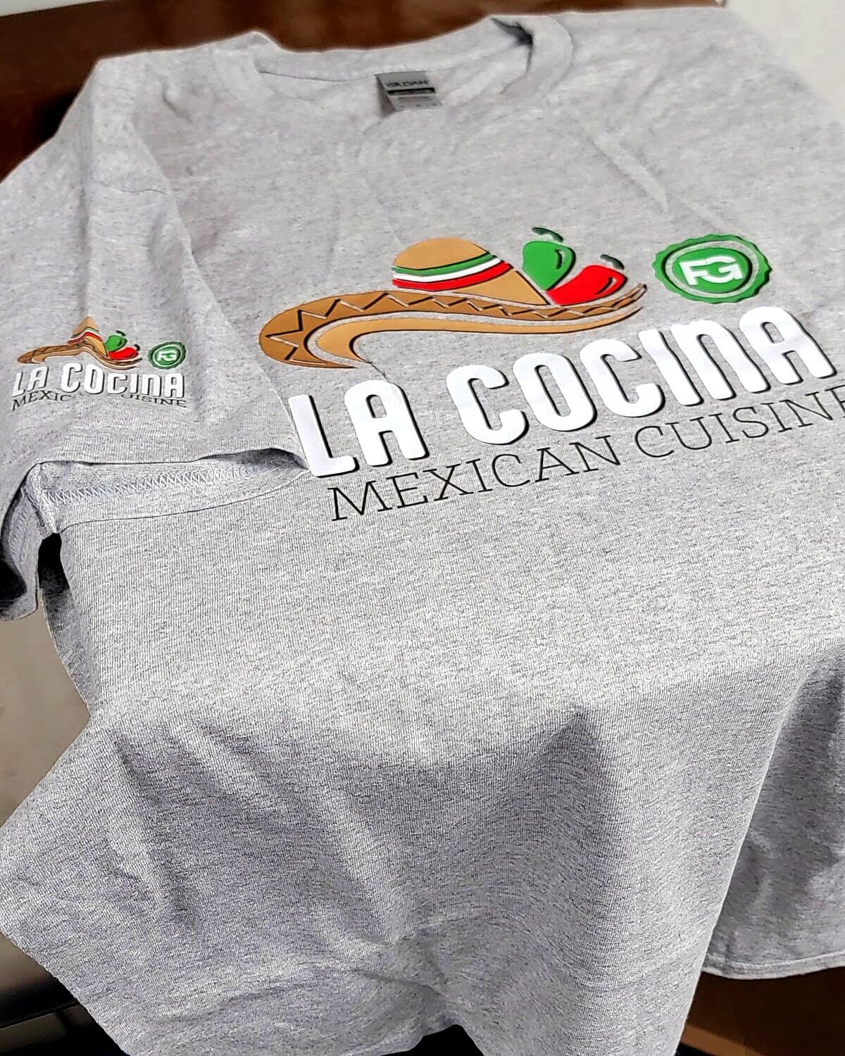 Gray staff t-shirt with a full-color restaurant logo on the front and sleeve, printed in Coatesville, PA