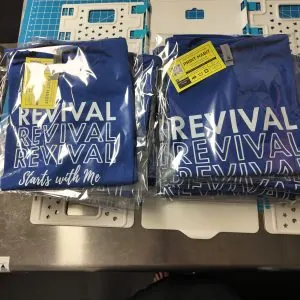 Custom printed t-shirts folded and bagged on a stainless steel table
