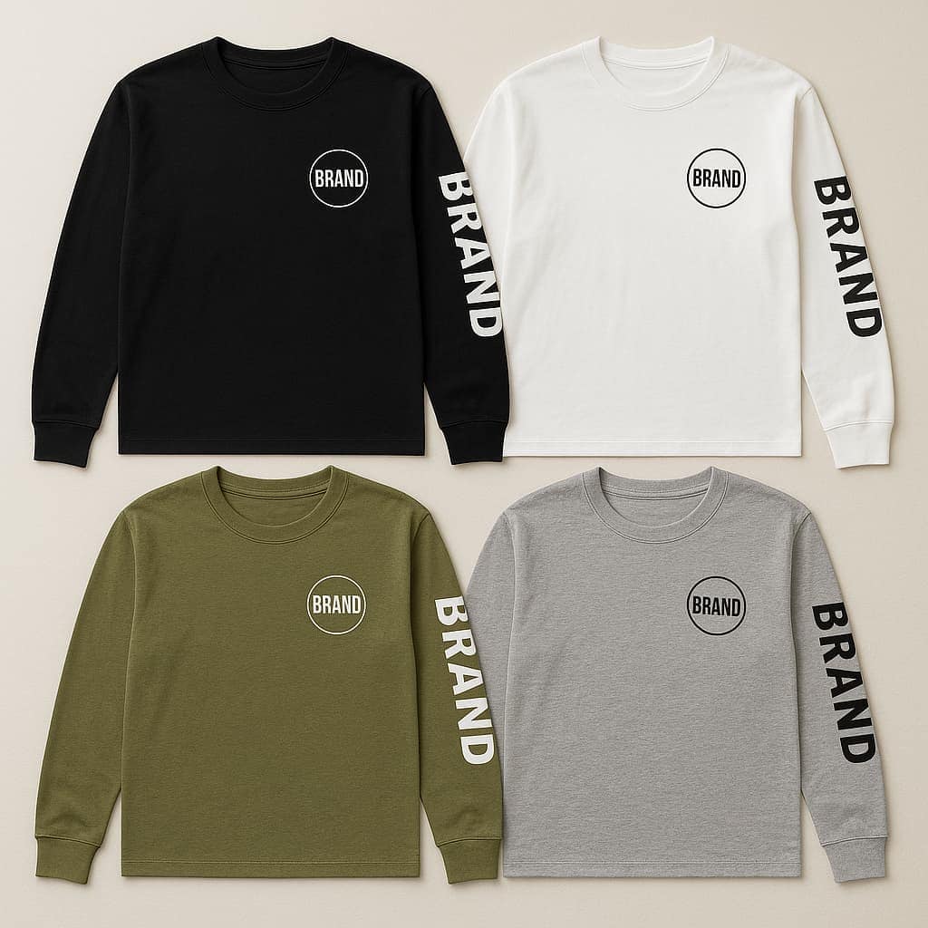 Flat lay of four long sleeve t-shirts in white, black, olive green, and heather gray, each with a chest logo and sleeve print, displayed on a neutral fabric background.
